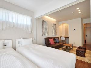a bedroom with a large white bed and a living room at Condominium・yuyuki in Yomitan