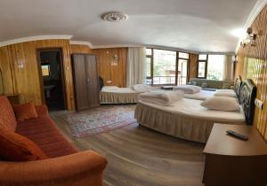 Habitación de hotel con 2 camas y sofá en Yeşilvadi Otel, en Ayder