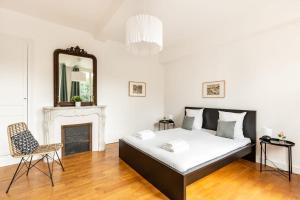 - une chambre avec un lit, un miroir et une chaise dans l'établissement Hypolite 1  New - Appartement Cocooning - 80 mètres du Port d' Honfleur, à Honfleur