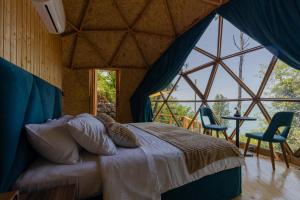a bedroom with a bed in a room with large windows at Glamping Martini Kvariati in Batumi