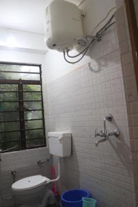 uma casa de banho com um WC, uma luz e uma janela em RHODODENDRON stay em Darjeeling