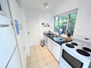 uma cozinha com um fogão e um lavatório em Tiri Cottage - Sea Views in Oneroa by Waiheke Unlimited em Oneroa