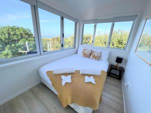 - une chambre avec un lit doté d'oreillers et de fenêtres dans l'établissement Tiri Cottage - Sea Views in Oneroa by Waiheke Unlimited, à Oneroa
