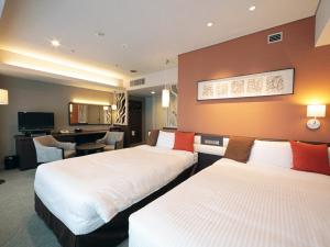 a hotel room with two beds and a desk at Hotel Monarque Tottori in Tottori