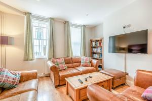 a living room with leather furniture and a flat screen tv at Ty Castell in Caernarfon