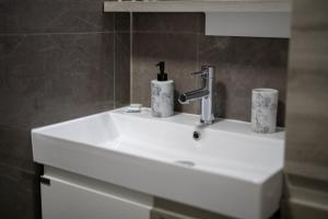 a white bathroom sink with two cups on it at Konka Apartment Tuzla in Tuzla