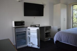 um quarto com uma cama e uma televisão na parede em Riviana Motel em Deniliquin