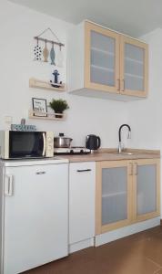 a kitchen with white cabinets and a microwave at Apartamenty Amarel - Wilk Morski in Stegna