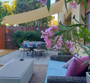 a patio with a table and chairs and pink flowers at Casa Francesca Altea piscina y aparcamiento privado in Altea