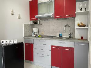 uma cozinha com armários vermelhos e um frigorífico preto em Luxory Apartaments 2 em Costinesti