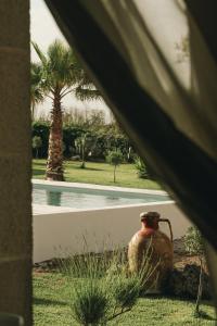 um vaso sentado na relva ao lado de uma piscina em Masseria Petrusella em Giuggianello