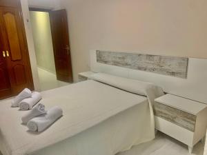 una camera da letto bianca con due asciugamani su un letto di Vivienda con fines turísticos Mi dulce Triana a Úbeda