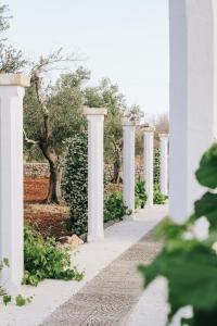 eine Reihe weißer Säulen auf einem weißen Gebäude in der Unterkunft Masseria Petrusella in Giuggianello