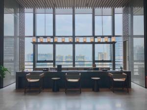 a restaurant with a bar with chairs and windows at Ascott M-City Foshan in Foshan