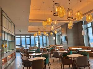 a restaurant with tables and chairs and chandeliers at Ascott M-City Foshan in Foshan