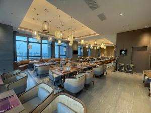 a restaurant with tables and chairs and windows at Ascott M-City Foshan in Foshan