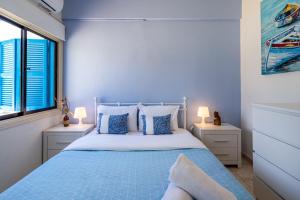 ein blaues Schlafzimmer mit einem Bett und zwei Fenstern in der Unterkunft Sea Breeze 1-BR Apt in Pyla in Pyla