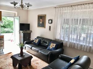 a living room with a black leather couch at Lovely Apartment in front of the Lake in Pogradec