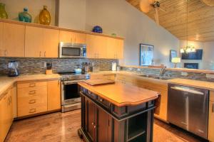 uma grande cozinha com armários de madeira e electrodomésticos de aço inoxidável em Vista Del Mar Condo - Oyhut Bay Seaside Village em Ocean Shores