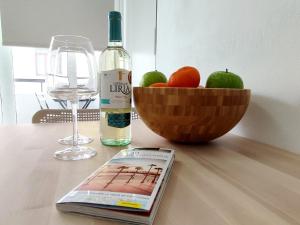 a bottle of wine and a book on a table with a bowl of fruit at Las Canteras Suite in Las Palmas de Gran Canaria