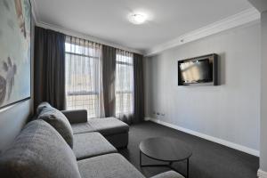a living room with a couch and a tv at KOZYGURU Sydney CBD Amazing View 2 Bed Family Apartment NHA653-702 in Sydney