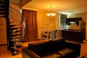 a living room with a couch and a table with chairs at Tat Place Hotel in Kuala Belait