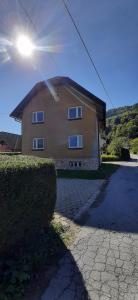 a house with the sun shining behind a hedge at Apartma Dana-Brinjtesa in Jesenice