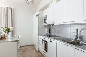 a white kitchen with white cabinets and a sink at Arctic Starry City Suite in Rovaniemi