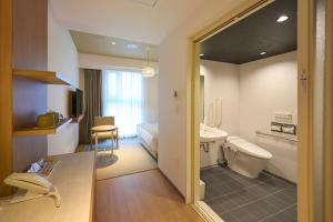 a bathroom with a sink and a toilet in a room at Hotel Resol Trinity Naha in Naha