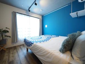 um quarto com uma cama com uma parede azul em Luana Shibuya em Tóquio