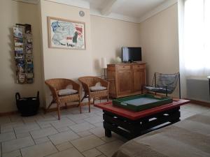 a living room with a tv and chairs and a table at Le gite de l'impassiflore in Méounes-lès-Montrieux