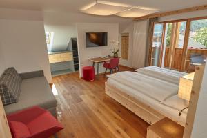 a bedroom with a bed and a desk and a table at Hotel Brötz in Rasùn di Sotto