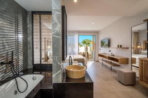 a bathroom with a bath tub and a bedroom at Stella Palace Aqua Park Resort in Hersonissos