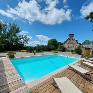 a swimming pool with a wooden deck and a house at Le Mas de Rigoulac chambre Zen SPA sur réservation in Bouyssounouse