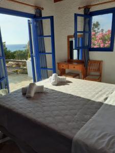 a bedroom with a large bed with blue framed windows at Villas Kalafatis Apartments in Kalafatis