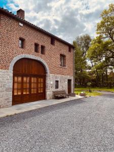 ein großes Backsteingebäude mit einer großen Holzgarage in der Unterkunft Grange de Ninie in Rochefort