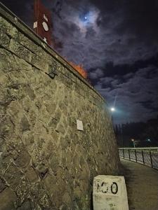 uma parede de pedra à noite com uma torre de relógio em Al Centesimo Chilometro - Ristoro del Pellegrino em Montefiascone