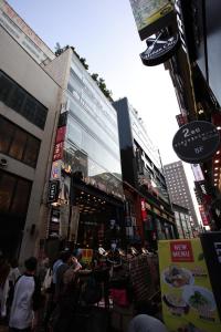 un grupo de personas sentadas en mesas frente a un edificio en Ekonomy Hotel Myeongdong Premier, en Seúl