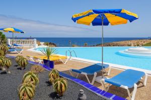 a pool with chairs and umbrellas and the ocean at Oböna Castillo de Papagayo, Complejo Nudista FKK-Nudist Resort in Charco del Palo