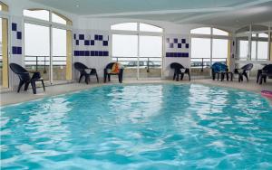 a large swimming pool with chairs and windows at Madame Vacances Les Terrasses De La Plage in Cayeux-sur-Mer