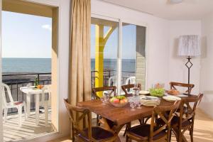 a dining room with a table and a view of the ocean at Madame Vacances Les Terrasses De La Plage in Cayeux-sur-Mer