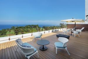 una terraza con sillas, mesas y sombrilla en Kawana Hotel en Ito