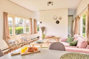 uma sala de estar com um sofá rosa e cadeiras em Chalet Terra Incognito em Westerland