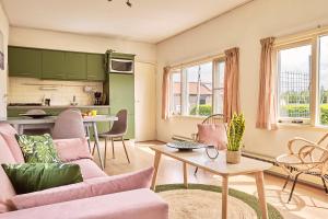 uma sala de estar com mobiliário rosa e uma cozinha em Chalet Terra Incognito em Westerland