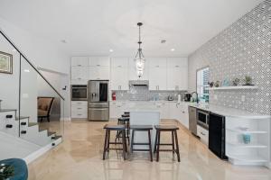 a large kitchen with white cabinets and bar stools at Las Olas Villa with HEATED Salt Water Pool in Fort Lauderdale
