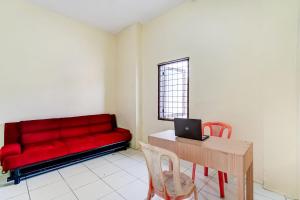 uma sala de estar com um sofá vermelho e uma mesa com um computador portátil em OYO 91110 Wilson Homestay em Medan
