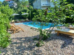 a backyard with a pool with a bench and a tree at Apartmani ,,Vasa ,, 3 in Soko Banja
