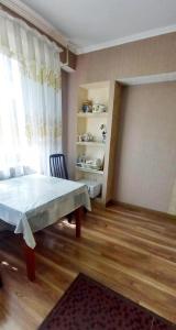 ein Wohnzimmer mit einem Tisch und einem Fenster in der Unterkunft Одна комнатная квартира в центре in Schymkent