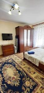 1 dormitorio con 1 cama, TV y alfombra en Одна комнатная квартира в центре en Shymkent