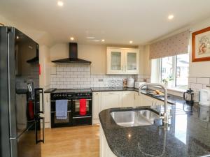 a kitchen with a sink and a stove at Ash Tree Cottage in Holsworthy